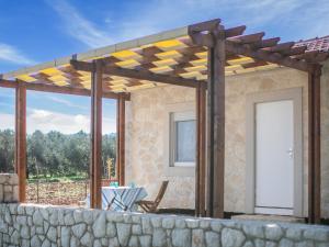 eine hölzerne Pergola auf einem Haus mit einer Steinmauer in der Unterkunft Secluded Holiday Home in Pa man with Sea nearby in Pašman