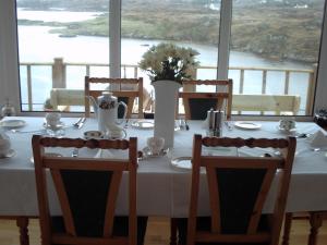 een witte tafel met stoelen en een vaas met bloemen bij Teach Donncadh B&B in Kincasslagh