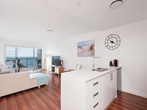 a kitchen and living room with a couch and a clock at 501 The Shoal in Shoal Bay