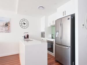 a white kitchen with a stainless steel refrigerator at 501 The Shoal in Shoal Bay