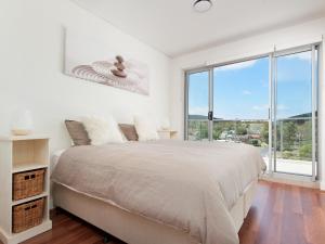 um quarto branco com uma cama grande e janelas grandes em 501 The Shoal em Shoal Bay