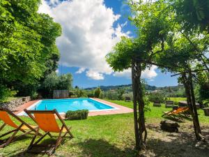 vista su una piscina con sedie e alberi di Pretty Farmhouse in Bacchereto with Swimming Pool a Carmignano