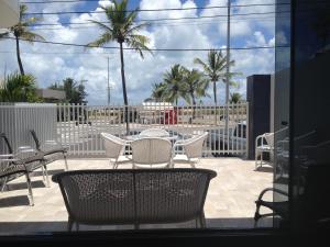 a patio with a table and chairs and palm trees at Hotel Praia e Mar in Aracaju