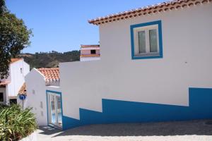 una casa bianca e blu con una porta blu di Sudoeste Guest House a Odeceixe