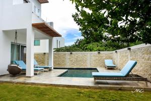 a swimming pool with two blue chairs next to a wall at Puerto Morelos, Villa Mimi, Private Pool in Puerto Morelos