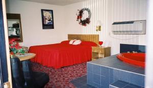 a bedroom with a red bed and a tub at Spring Hill Motel in Wisconsin Dells