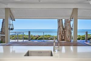 Una cocina con fregadero y vista al mar. en Decked Out By The Sea, en Clifton Beach
