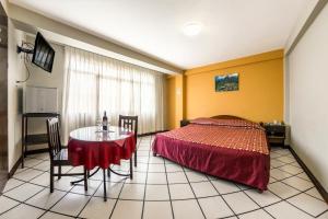 a bedroom with a bed and a table and chairs at Hostal Primavera in Chosica