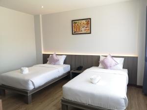 2 Betten in einem Zimmer mit weißer Bettwäsche und rosa Kissen in der Unterkunft Orchid Residence Suratthani in Surat Thani