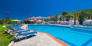 a large swimming pool with lounge chairs and umbrellas at Halkidiki Palace in Polykhrono