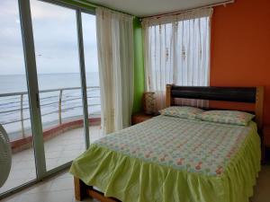 a bedroom with a bed and a balcony with the ocean at Arco Iris Atacames in Atacames