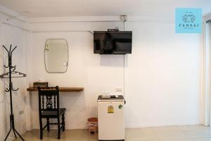 Habitación con TV en la pared y nevera. en Fahsai Bay Villa, en Ao Nam Mao