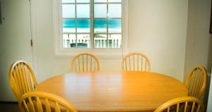 uma mesa de madeira com cadeiras e vista para o oceano em The Beach Cottages em San Diego