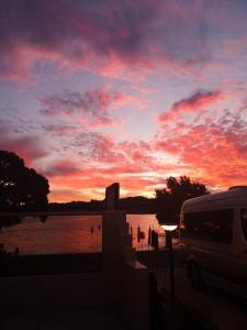 un furgone parcheggiato accanto a un corpo d'acqua con un tramonto di Paku Lodge Resort a Tairua