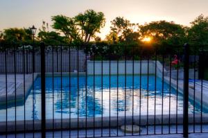 a swimming pool behind a fence at sunset at Kerry Lodge Bed & Breakfast in Napier