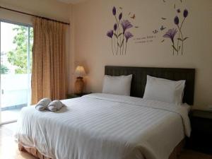 een slaapkamer met een groot wit bed met paarse bloemen aan de muur bij Baan Suksiri Hotel in Hua Hin
