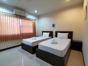 una camera con due letti con lenzuola bianche e una finestra di Nestvilla Khok-kloi Phang-nga a Ban Nai