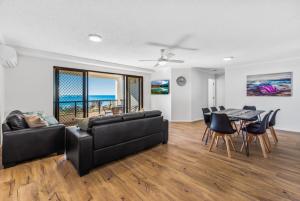 a living room with a couch and a table with chairs at San Marino by the Sea Apartments in Marcoola