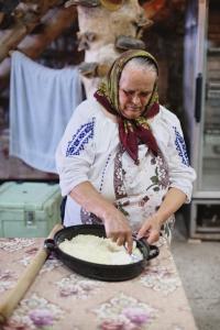 eine Frau bereitet Essen in einer Pfanne auf einem Tisch zu in der Unterkunft Cabana Virful Muntelui in Câmpeni + 239 Fotos