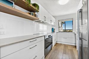 a kitchen with a stove, refrigerator, sink and cabinets at San Marino by the Sea Apartments in Marcoola