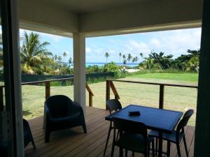 eine Veranda mit einem Tisch und Stühlen sowie Meerblick in der Unterkunft SNP- PALMS in Papetoai