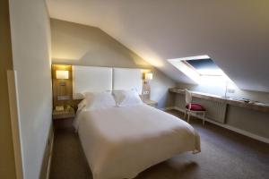 Un dormitorio con una gran cama blanca y una ventana en Hotel Los Lagos Nature, en Cangas de Onís