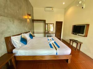 a bedroom with a bed with blue pillows and a television at Home Inn Pai Garden in Pai