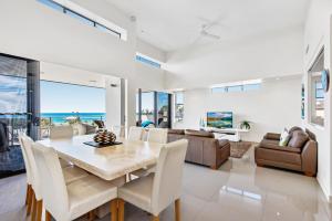 a dining room and living room with a table and chairs at Beaches on Maroochy 1 Beach Parade in Maroochydore