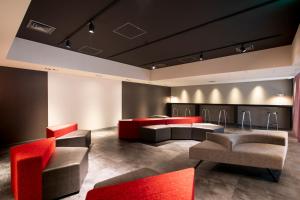 a waiting room with red chairs and couches at Cross Hotel Osaka in Osaka