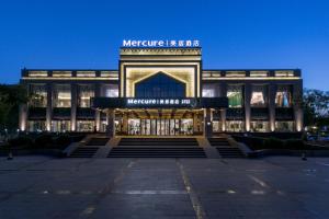 a large building with a sign on the front of it at Mercure Turpan Downtown in Turfan