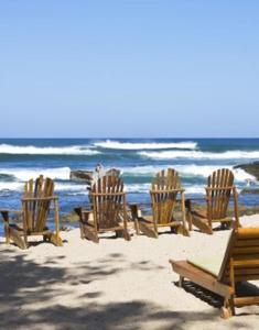a beach area with chairs, tables and umbrellas at Sueño del Mar Beachfront Hotel in Tamarindo