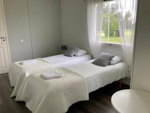 two beds in a room with a window at Huoneistomajoitus Koto, LaatuLomat in Juva