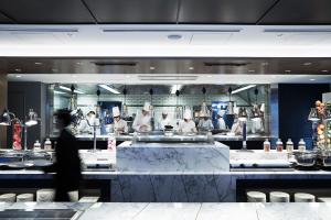 a man walking through a kitchen with chefs in the background at Cross Hotel Osaka in Osaka