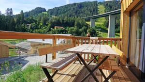 una mesa de madera y un banco en el balcón de una casa en Bergeralm Chalets by ALPS RESORTS, en Steinach am Brenner