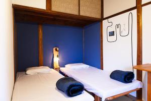 two beds in a room with blue walls at Machicado in Tamano