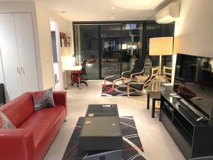 ein Wohnzimmer mit einem roten Sofa und einem TV in der Unterkunft StayCentral - Spacious Seaviews Port Melbourne in Melbourne