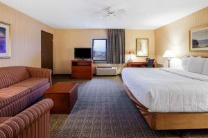 a hotel room with a large bed and a couch at La Quinta Inn by Wyndham Detroit Southgate in Southgate
