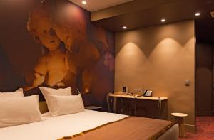 a hotel room with a bed with a painting on the wall at Hotel Sixteen Paris Montrouge in Montrouge