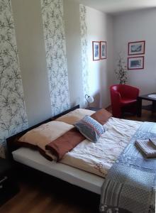uma cama num quarto com uma cadeira vermelha em Kozi Lasek em Koluszki