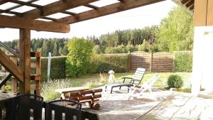 a patio with two chairs and a table and a bench at Ferienwohnung Steinwald Ausläufer mit Blick auf Kösseine in Waldershof