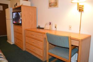 a room with a desk with a television and a dresser at Purple Sage Motel in Snyder