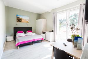 sypialnia z łóżkiem z różowymi poduszkami i biurkiem w obiekcie Apartamenty Za Regą w mieście Mrzeżyno