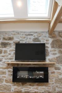 TV de pantalla plana en una pared de piedra en Bryher Cottage en Paul