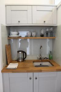 encimera de cocina con fregadero y armarios blancos en Bryher Cottage en Paul