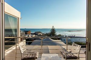 a balcony with two chairs and a view of the ocean at Blaauw Village Guest House in Bloubergstrand