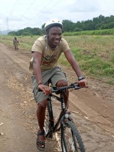 Mikumi Faru Tented Camp في Morogoro: رجل يركب دراجة على طريق ترابي