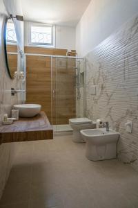 y baño con 2 aseos, ducha y lavamanos. en Riviera Rooms, en Alghero