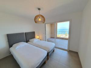 Dos camas en una habitación con vista al mar. en Domaine A Mortella T2, en Saint-Florent