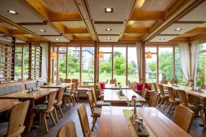 a restaurant with wooden tables and chairs and windows at Hotel Alpenblick in Ohlstadt