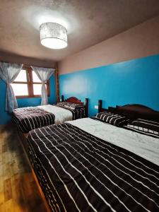 a bedroom with three beds and a blue wall at My Home Apartment - Villa Dahlia Apartment in Cameron Highlands